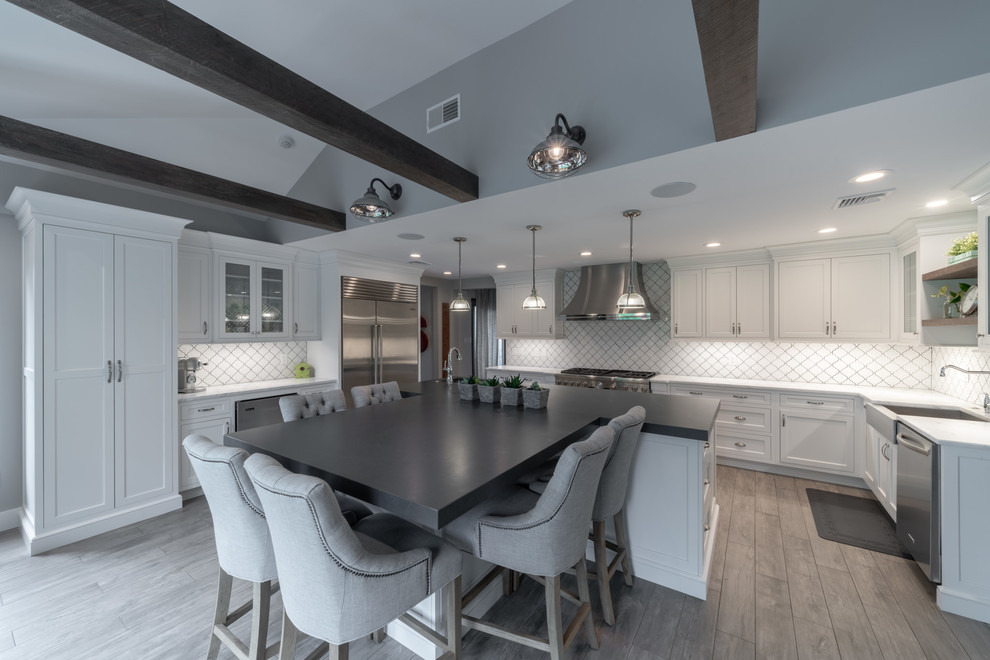 Inspiration for an expansive modern kitchen in Other with shaker cabinets, white cabinets, marble benchtops, white splashback, porcelain splashback, stainless steel appliances, medium hardwood floors, with island, grey floor, white benchtop and a farmhouse sink.