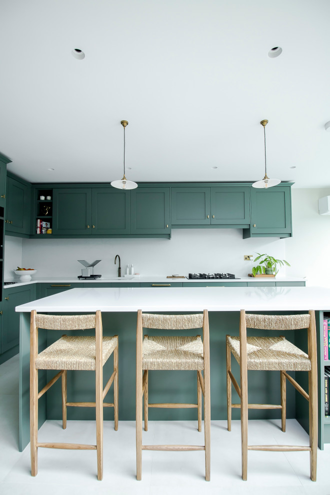 Inspiration for a mid-sized modern l-shaped open plan kitchen in Surrey with an integrated sink, shaker cabinets, green cabinets, quartzite benchtops, white splashback, limestone splashback, panelled appliances, concrete floors, a peninsula, grey floor and white benchtop.