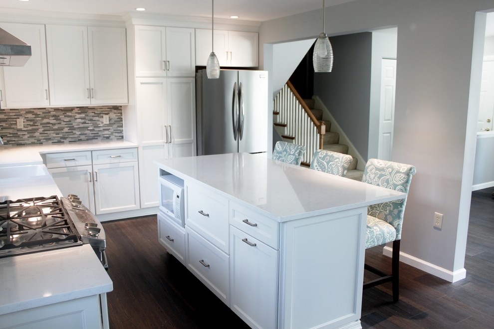 Photo of a mid-sized transitional l-shaped eat-in kitchen in Philadelphia with a farmhouse sink, shaker cabinets, white cabinets, quartz benchtops, blue splashback, mosaic tile splashback, stainless steel appliances, vinyl floors, with island and brown floor.