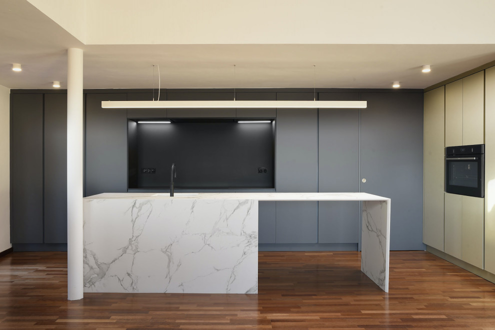 This is an example of a large modern single-wall eat-in kitchen in Barcelona with recessed-panel cabinets, green cabinets, tile benchtops, white splashback, black appliances, dark hardwood floors, with island and white benchtop.