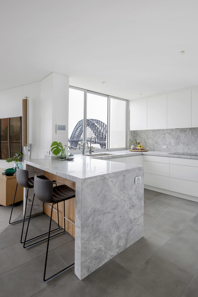 This is an example of a mid-sized modern u-shaped separate kitchen in Sydney with an undermount sink, flat-panel cabinets, white cabinets, granite benchtops, grey splashback, stone slab splashback, stainless steel appliances, ceramic floors, a peninsula, grey floor and grey benchtop.