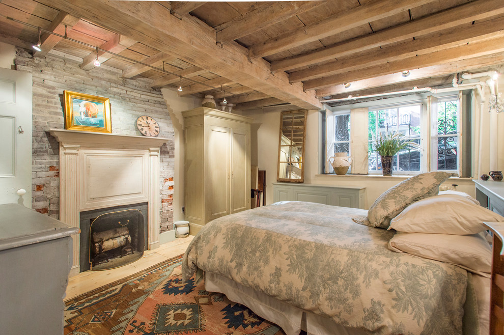Traditional bedroom in Boston with beige walls, light hardwood floors and a standard fireplace.