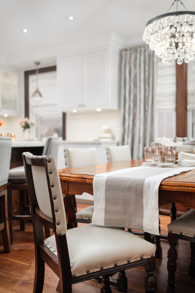 Inspiration for a mid-sized transitional u-shaped medium tone wood floor and brown floor eat-in kitchen remodel in Toronto with a farmhouse sink, recessed-panel cabinets, gray cabinets, quartzite countertops, white backsplash, subway tile backsplash, stainless steel appliances, an island and beige countertops