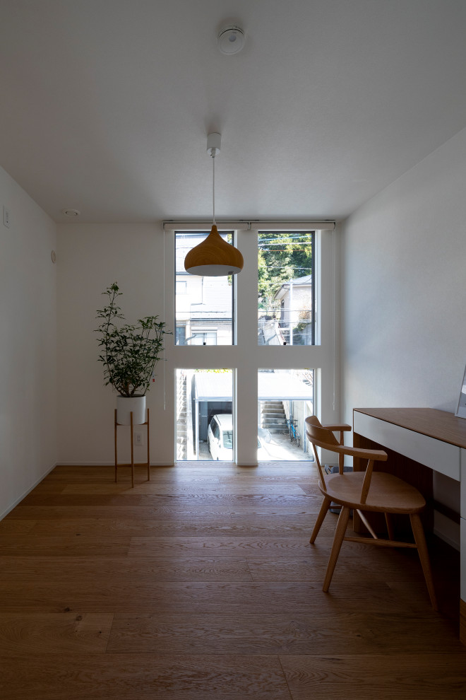 Bild på ett mellanstort skandinaviskt könsneutralt tonårsrum kombinerat med skrivbord, med vita väggar, ljust trägolv och brunt golv