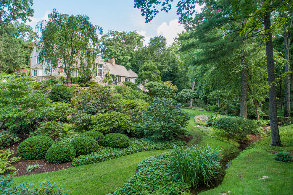 This is an example of a large traditional sloped full sun formal garden for summer in New York with with flowerbed.