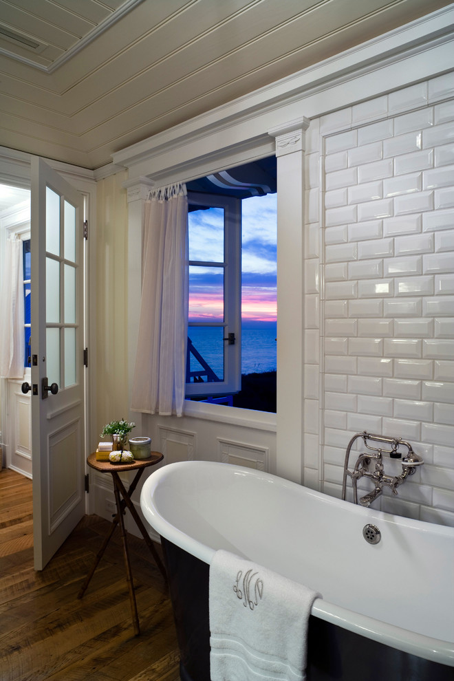 Inspiration for a beach style bathroom in New York with white tile, subway tile, yellow walls, dark hardwood floors and a freestanding tub.