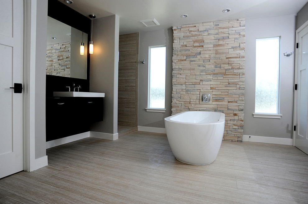 Inspiration for a large contemporary master bathroom in Los Angeles with flat-panel cabinets, black cabinets, a freestanding tub, an alcove shower, stone tile, grey walls, porcelain floors, an integrated sink, beige tile, solid surface benchtops, beige floor and an open shower.