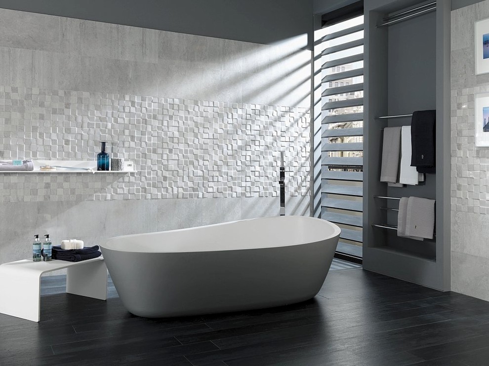 パースにあるラグジュアリーな広いインダストリアルスタイルのおしゃれなマスターバスルーム (グレーのタイル、置き型浴槽、セラミックタイル、グレーの壁、磁器タイルの床、オープンシェルフ、白いキャビネット) の写真