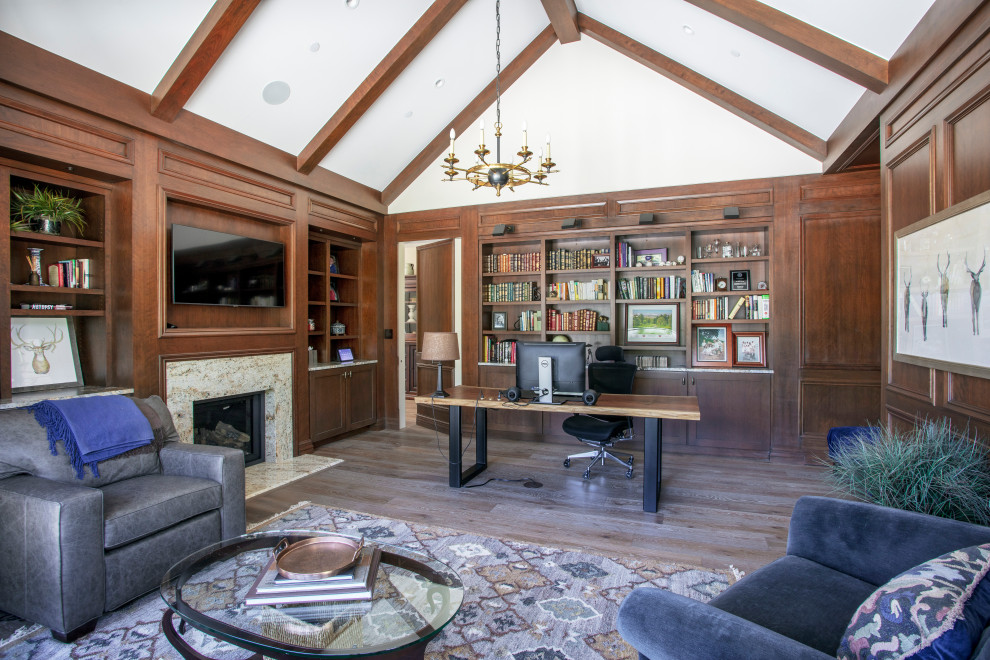 Design ideas for an expansive traditional study room in Denver with brown walls, medium hardwood floors, a standard fireplace, a stone fireplace surround, a freestanding desk, grey floor, exposed beam and decorative wall panelling.