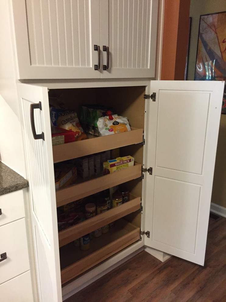 Mid-sized transitional u-shaped medium tone wood floor eat-in kitchen photo with a single-bowl sink, recessed-panel cabinets, white cabinets, granite countertops, brown backsplash, ceramic backsplash, stainless steel appliances and no island