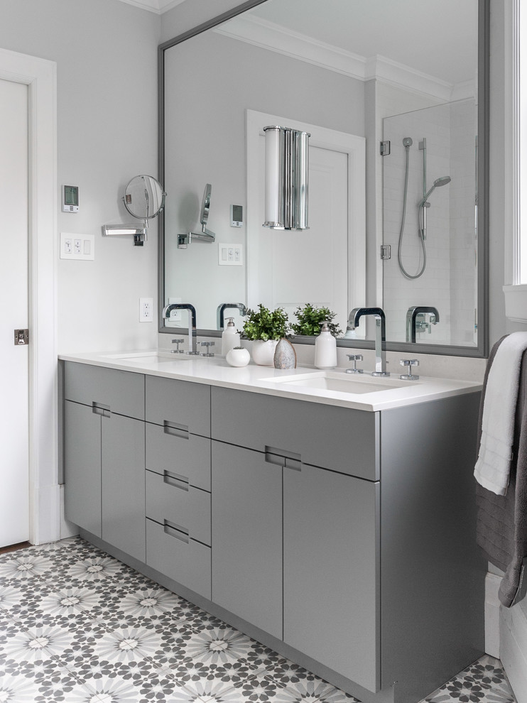 This is an example of a mid-sized contemporary master bathroom in Montreal with flat-panel cabinets, grey cabinets, a corner shower, a one-piece toilet, white tile, subway tile, grey walls, ceramic floors, an undermount sink, engineered quartz benchtops, grey floor, a hinged shower door and grey benchtops.