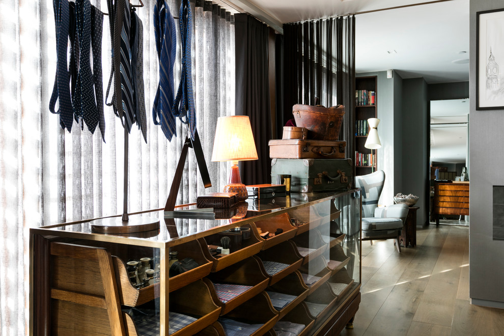 Photo of a contemporary men's storage and wardrobe in London with open cabinets, medium wood cabinets and medium hardwood floors.