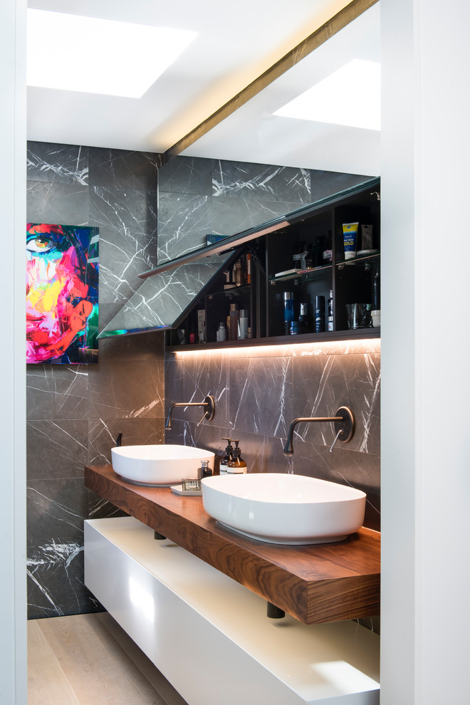 Small contemporary master bathroom in Sydney with white cabinets, an open shower, a wall-mount toilet, gray tile, stone tile, grey walls, light hardwood floors, a vessel sink, wood benchtops, an open shower, beige floor, brown benchtops and flat-panel cabinets.