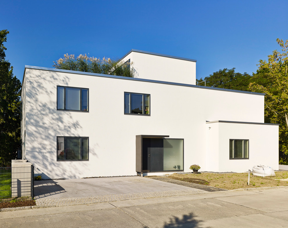 Photo of a mid-sized contemporary three-storey white exterior in Berlin with a flat roof.