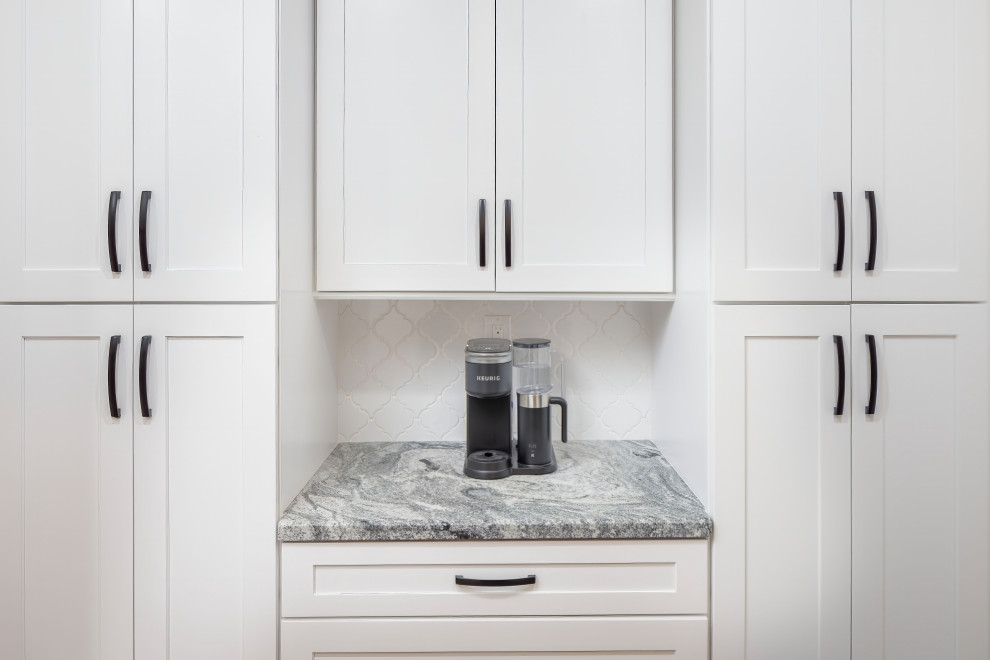 Inredning av ett klassiskt stort grå grått kök, med en enkel diskho, skåp i shakerstil, blå skåp, granitbänkskiva, vitt stänkskydd, stänkskydd i keramik, svarta vitvaror, laminatgolv, en köksö och blått golv