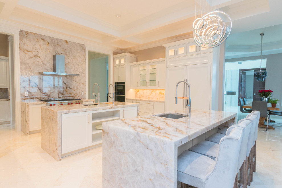 Design ideas for an expansive transitional u-shaped open plan kitchen in Other with an undermount sink, flat-panel cabinets, white cabinets, quartzite benchtops, white splashback, stone slab splashback, marble floors, multiple islands and white floor.