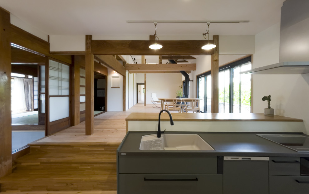Cette image montre une cuisine ouverte linéaire de taille moyenne avec des portes de placards vertess, parquet clair, îlot et un plafond en papier peint.