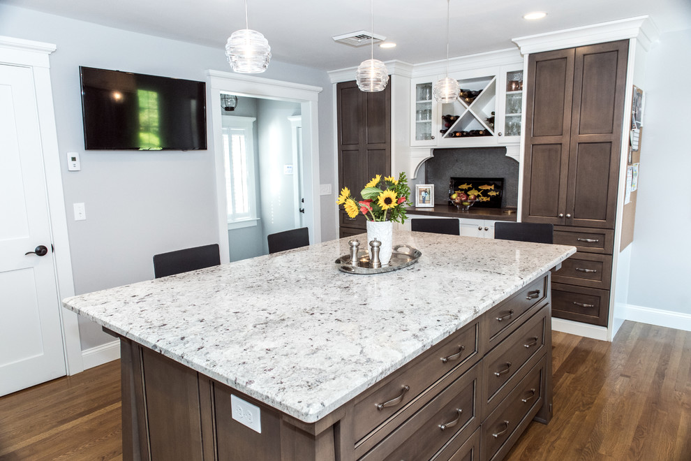 Inspiration for a mid-sized transitional u-shaped medium tone wood floor enclosed kitchen remodel in Providence with a double-bowl sink, white cabinets, granite countertops, white backsplash, subway tile backsplash, stainless steel appliances, an island and recessed-panel cabinets