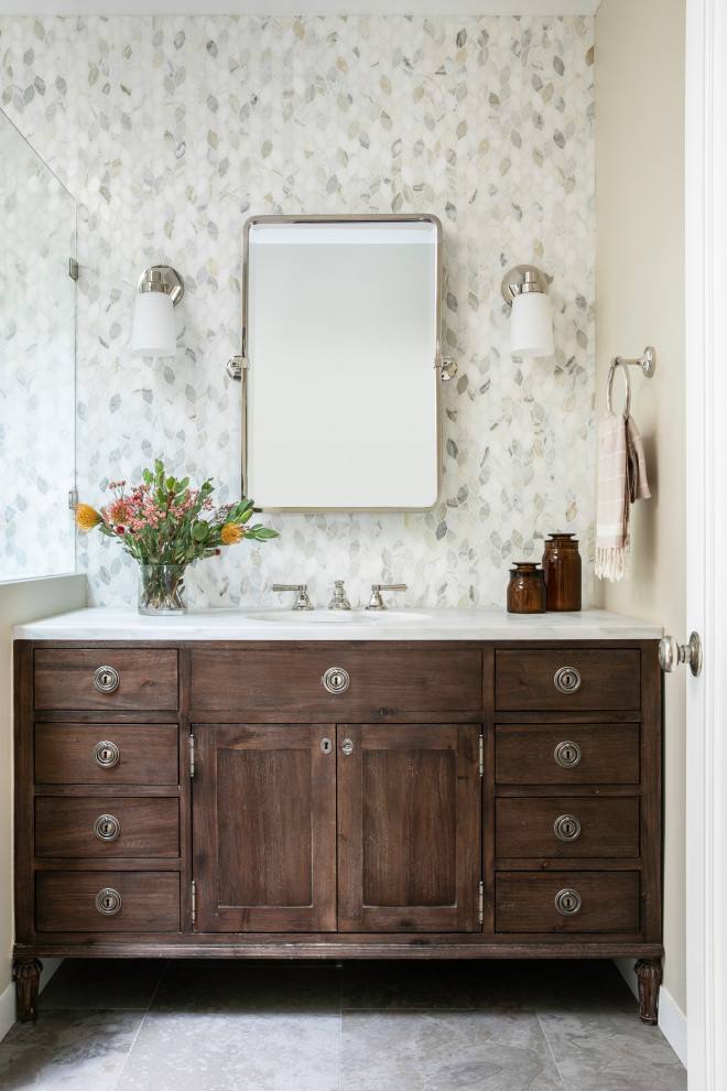 This is an example of a mid-sized traditional master bathroom in San Francisco with brown cabinets, an open shower, a one-piece toilet, beige tile, marble, beige walls, cement tiles, a drop-in sink, marble benchtops, grey floor, a hinged shower door, white benchtops, a shower seat, a single vanity, a built-in vanity and shaker cabinets.