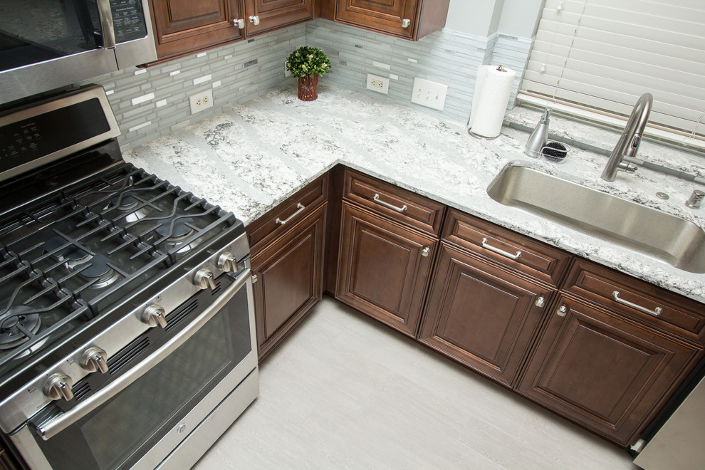 Open concept kitchen - mid-sized transitional l-shaped porcelain tile and gray floor open concept kitchen idea in Houston with a single-bowl sink, raised-panel cabinets, medium tone wood cabinets, quartz countertops, mosaic tile backsplash, stainless steel appliances, two islands and white backsplash