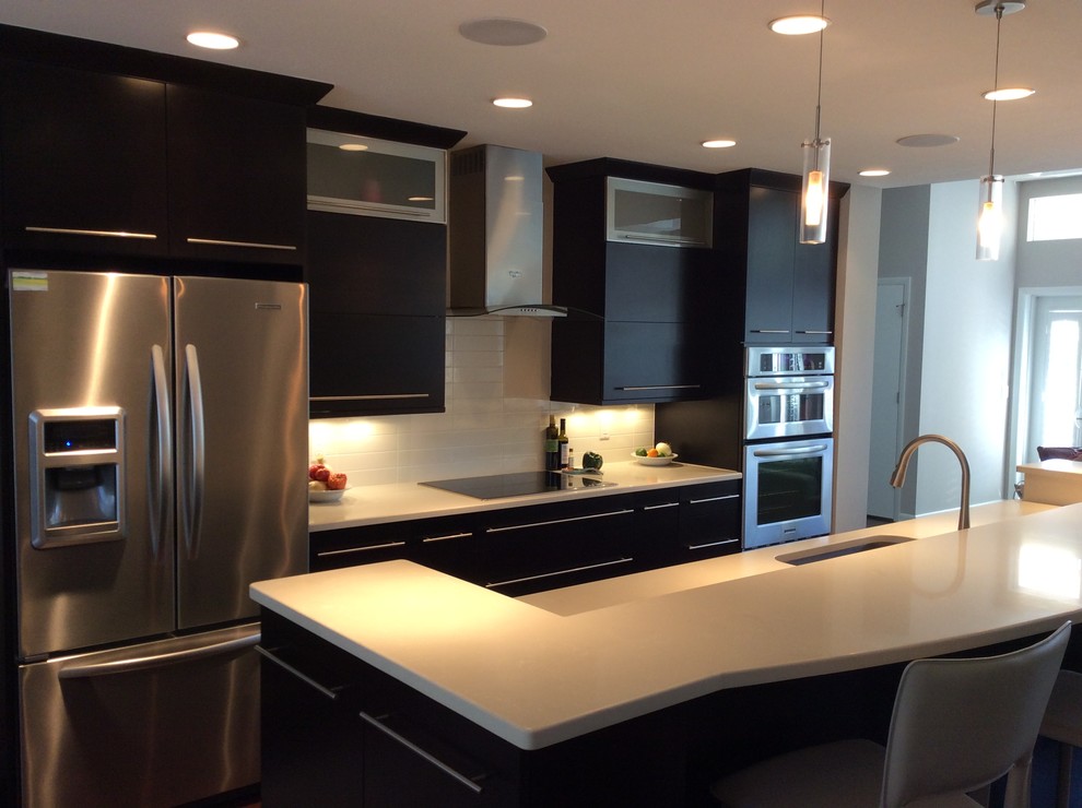 Large transitional galley eat-in kitchen photo in Chicago with an undermount sink, flat-panel cabinets, black cabinets, solid surface countertops, white backsplash, glass tile backsplash, stainless steel appliances and an island
