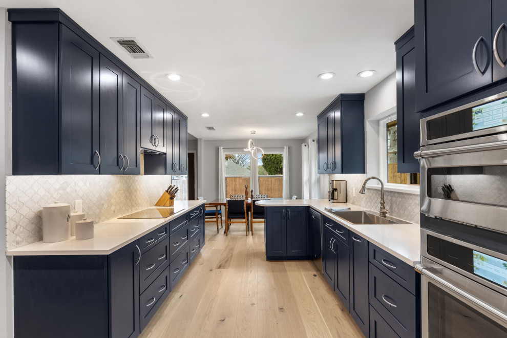 Mid-sized modern kitchen in Dallas with stainless steel appliances and light hardwood floors.