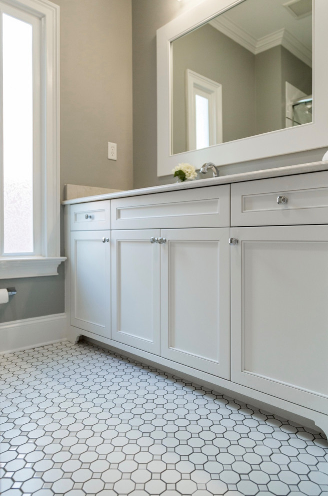 Design ideas for a mid-sized traditional 3/4 bathroom in Charlotte with shaker cabinets, white cabinets, a shower/bathtub combo, a two-piece toilet, gray tile, grey walls, ceramic floors, an undermount sink, quartzite benchtops, white floor, a sliding shower screen and white benchtops.