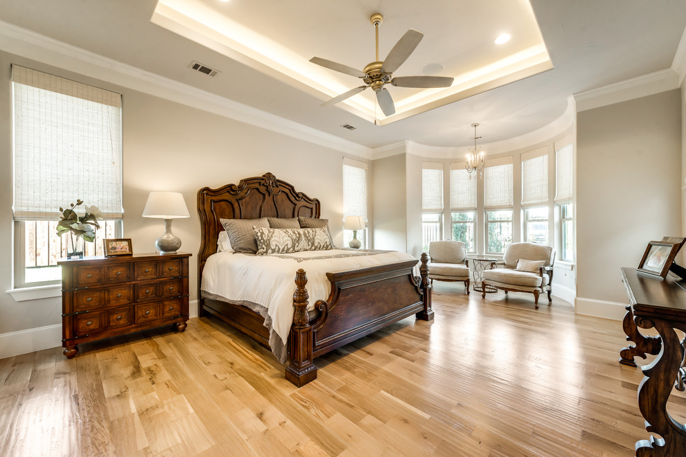 Inspiration for a large mediterranean master bedroom in Dallas with beige walls and light hardwood floors.