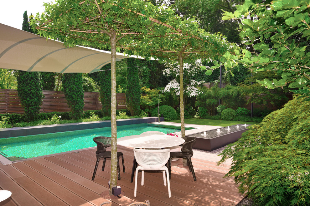 Design ideas for a large contemporary backyard deck in Cologne with a water feature and an awning.