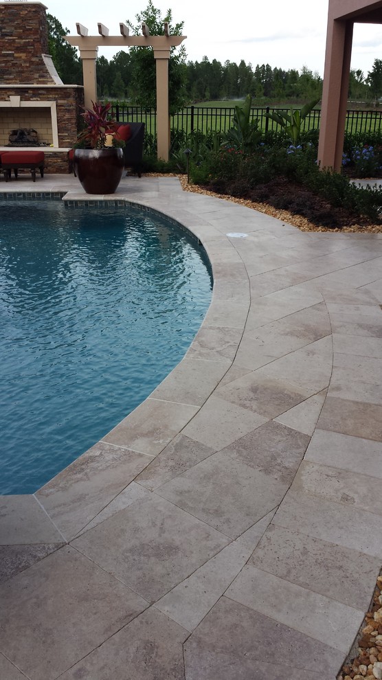 Mid-sized country backyard custom-shaped natural pool in Other with natural stone pavers.