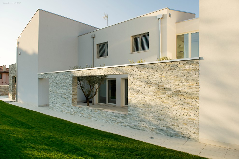 This is an example of a mid-sized contemporary two-storey concrete beige house exterior in Venice.