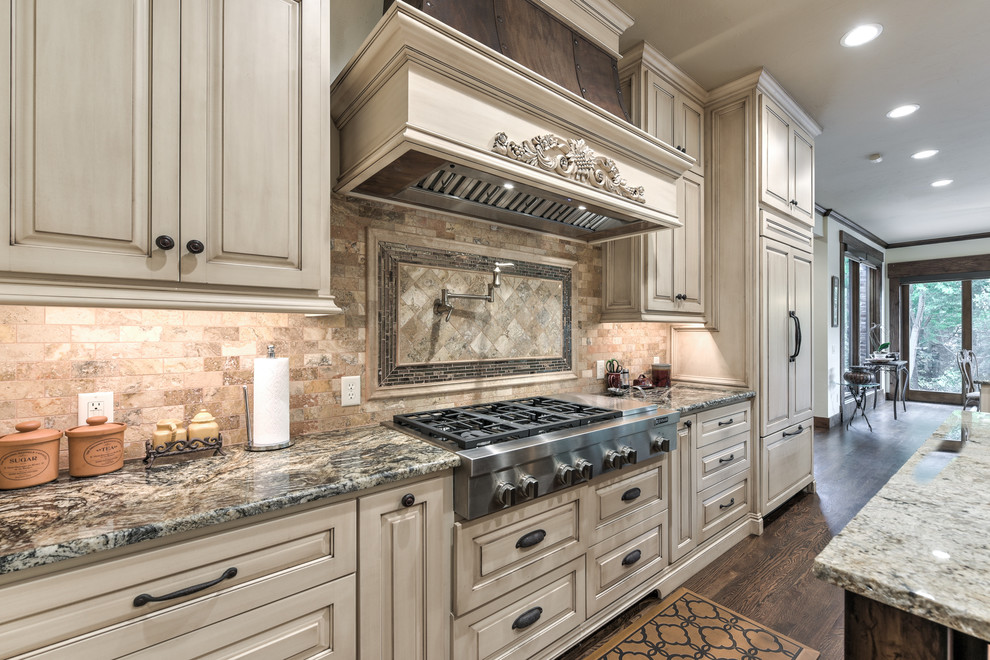 Design ideas for an expansive traditional galley separate kitchen in Oklahoma City with a farmhouse sink, raised-panel cabinets, light wood cabinets, granite benchtops, brown splashback, travertine splashback, stainless steel appliances, dark hardwood floors, with island and brown floor.