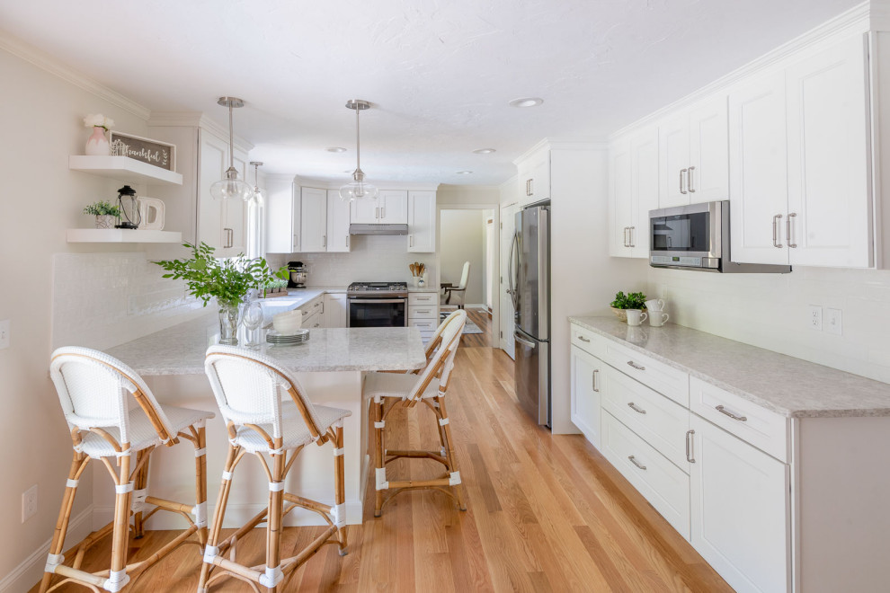 Kitchen - mid-sized transitional u-shaped medium tone wood floor and brown floor kitchen idea in Boston with an undermount sink, shaker cabinets, white cabinets, quartz countertops, white backsplash, ceramic backsplash, stainless steel appliances, a peninsula and gray countertops