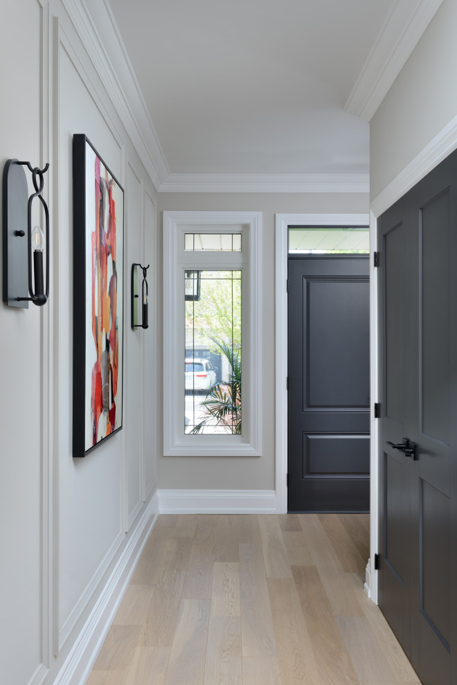 Idee per un corridoio chic di medie dimensioni con pareti beige, pavimento in legno massello medio, una porta singola, una porta nera e pavimento beige