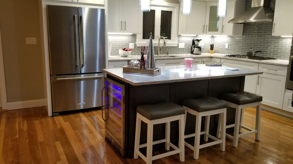 Mid-sized transitional l-shaped dark wood floor and brown floor open concept kitchen photo with an undermount sink, shaker cabinets, white cabinets, gray backsplash, stainless steel appliances, an island and white countertops