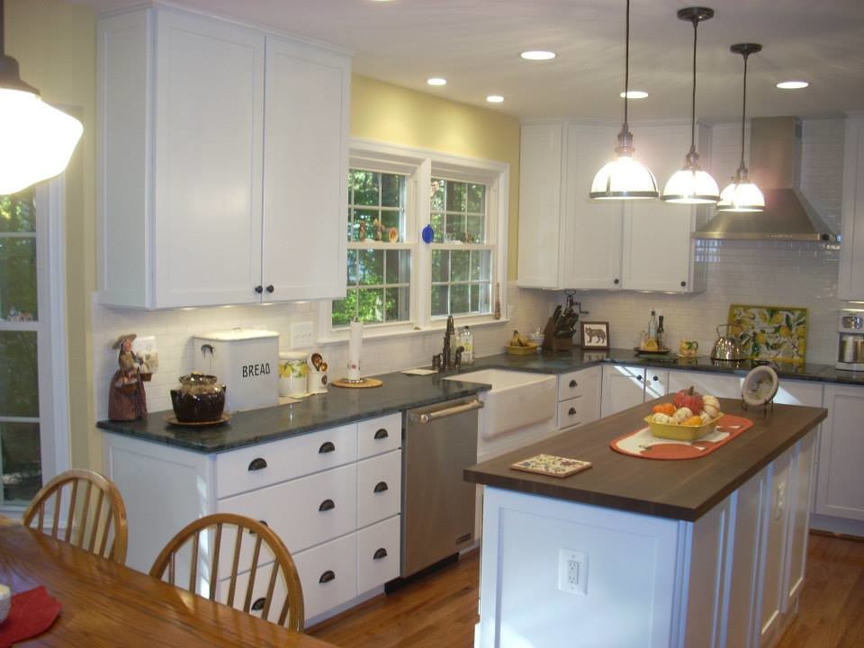 Inspiration for a small galley medium tone wood floor kitchen remodel in DC Metro with white cabinets, granite countertops, white backsplash, ceramic backsplash, stainless steel appliances and an island