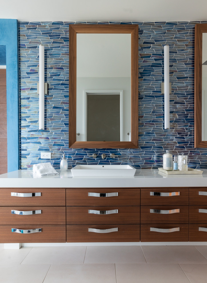 Photo of a beach style bathroom in Jacksonville with flat-panel cabinets, medium wood cabinets, blue tile, mosaic tile, a vessel sink, grey floor, white benchtops, a double vanity and a floating vanity.
