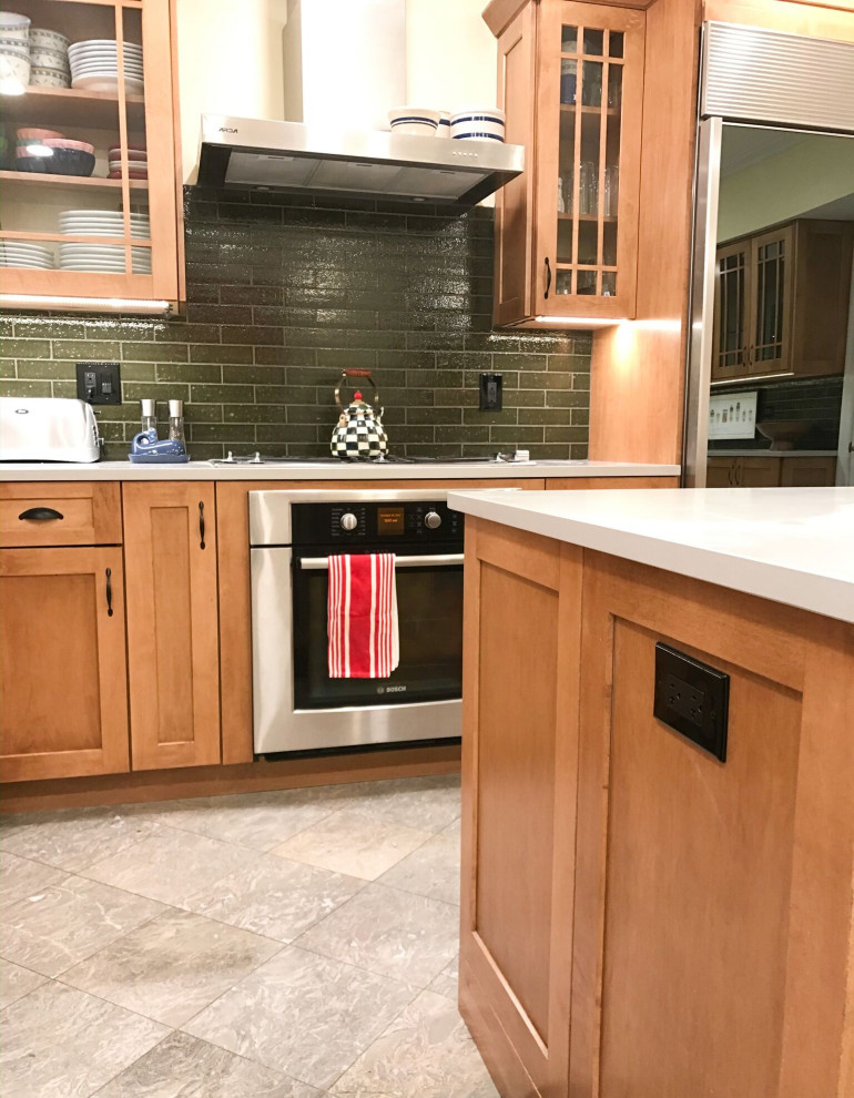 Eat-in kitchen - mid-sized transitional l-shaped eat-in kitchen idea in Chicago with an undermount sink, shaker cabinets, brown cabinets, green backsplash, stainless steel appliances, an island and gray countertops