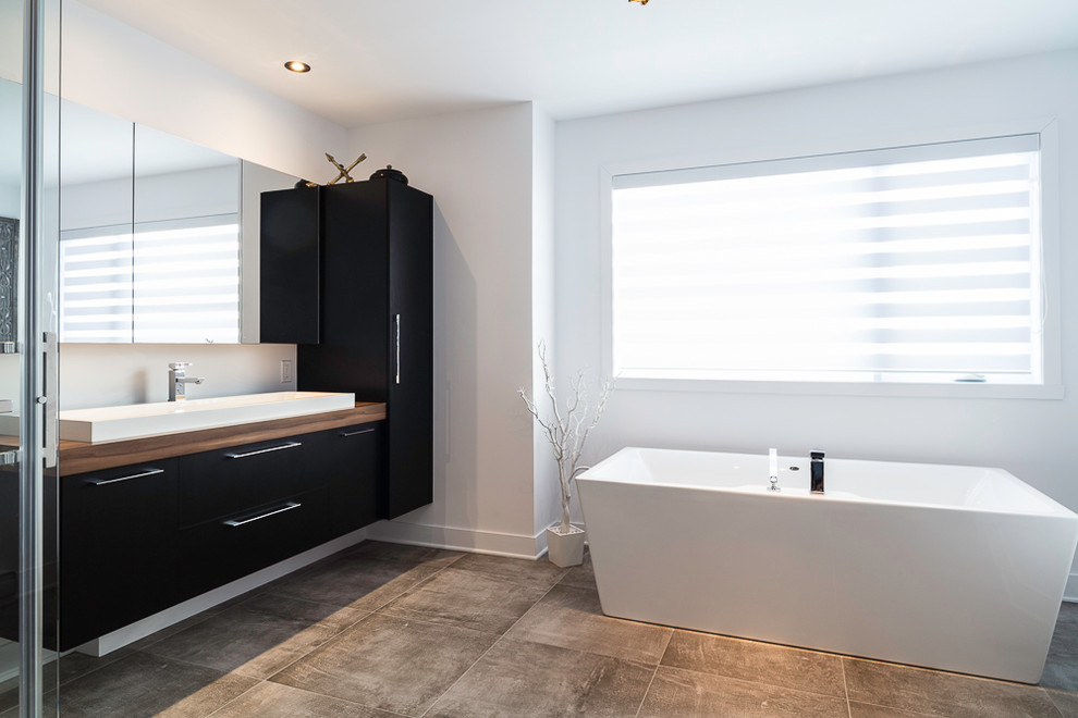 Design ideas for a mid-sized contemporary master wet room bathroom in Montreal with flat-panel cabinets, black cabinets, a japanese tub, black tile, ceramic tile, grey walls, a vessel sink, laminate benchtops, grey floor and a sliding shower screen.