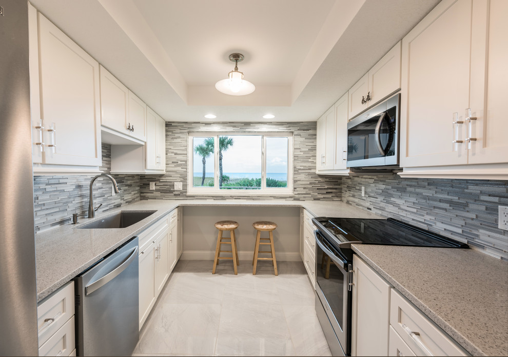Inspiration for a mid-sized transitional l-shaped porcelain tile and gray floor kitchen pantry remodel in Orlando with an undermount sink, shaker cabinets, white cabinets, quartz countertops, gray backsplash, mosaic tile backsplash, stainless steel appliances, no island and white countertops