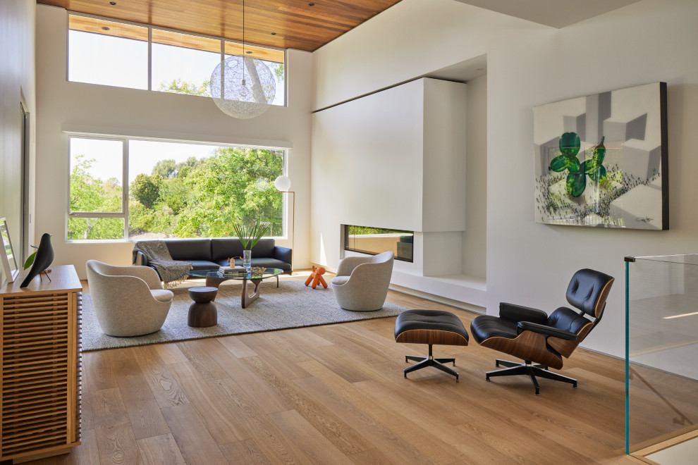 Inspiration for a large modern open concept living room in Los Angeles with white walls, medium hardwood floors, a ribbon fireplace, brown floor, wood and a plaster fireplace surround.