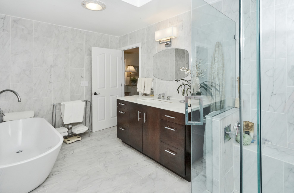 Transitional porcelain tile porcelain tile freestanding bathtub photo with flat-panel cabinets, dark wood cabinets, a two-piece toilet, an undermount sink, marble countertops and a hinged shower door