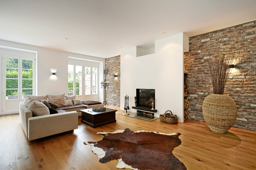 Inspiration for a large contemporary open concept family room in Dusseldorf with white walls, medium hardwood floors, a standard fireplace, a plaster fireplace surround and no tv.