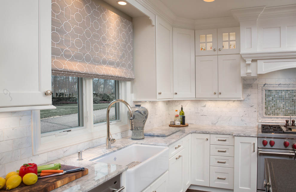This is an example of a large transitional l-shaped kitchen in Columbus with a farmhouse sink, white cabinets, granite benchtops, white splashback, stone tile splashback, stainless steel appliances, dark hardwood floors and with island.