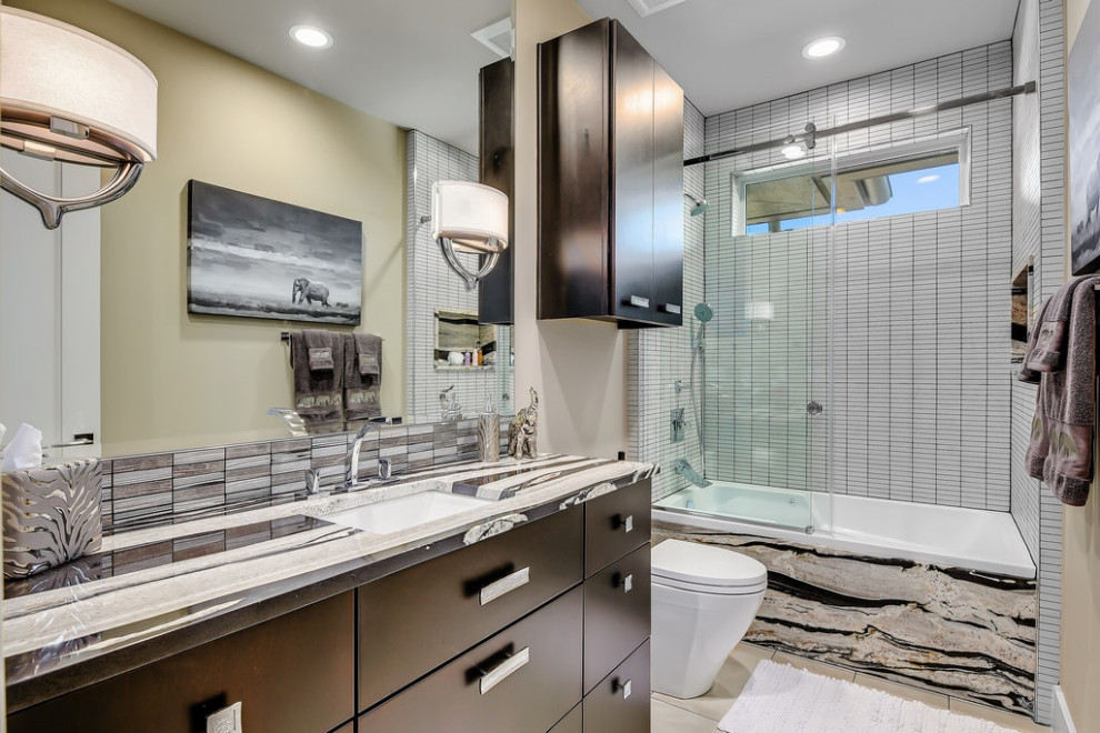 This is an example of a contemporary bathroom in Austin with flat-panel cabinets, dark wood cabinets, a shower/bathtub combo, white tile, mosaic tile, beige walls, an undermount sink, a sliding shower screen, grey benchtops, a single vanity and a built-in vanity.