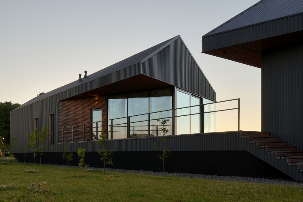 Свежая идея для дизайна: одноэтажный, серый частный загородный дом в скандинавском стиле с облицовкой из металла и серой крышей - отличное фото интерьера