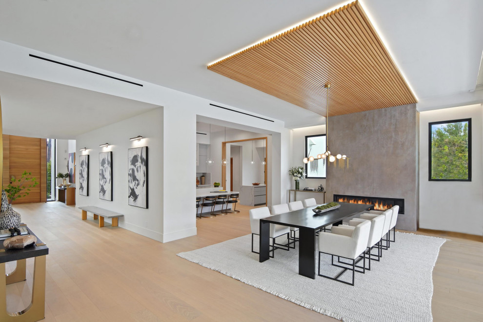 Exemple d'une grande salle à manger ouverte sur le salon moderne avec un mur blanc, parquet clair, une cheminée standard, un manteau de cheminée en plâtre, un sol beige et un plafond en bois.