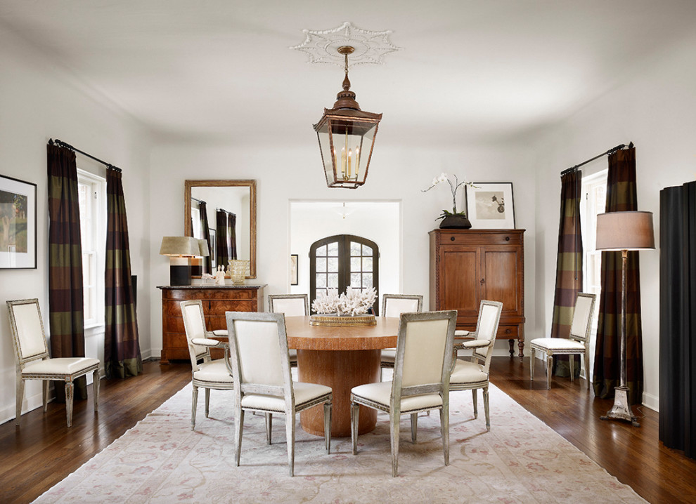 This is an example of a mid-sized mediterranean separate dining room in Austin with white walls, no fireplace, brown floor and dark hardwood floors.