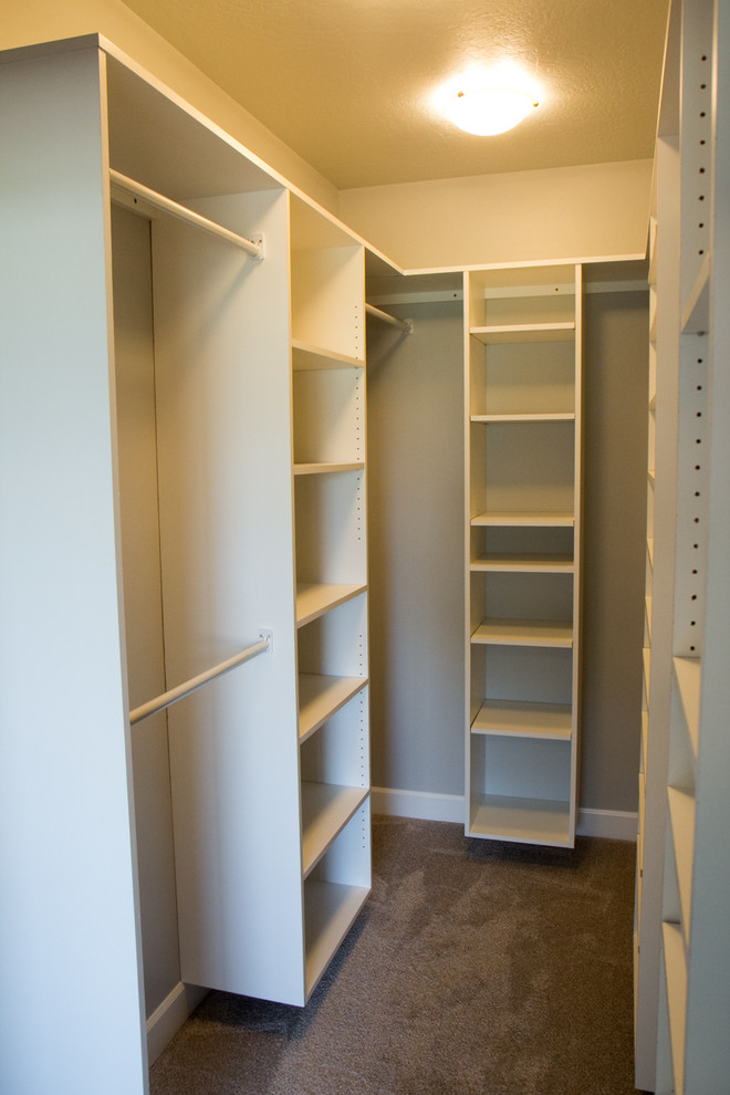 This is an example of a small traditional gender-neutral walk-in wardrobe in Other with white cabinets and carpet.