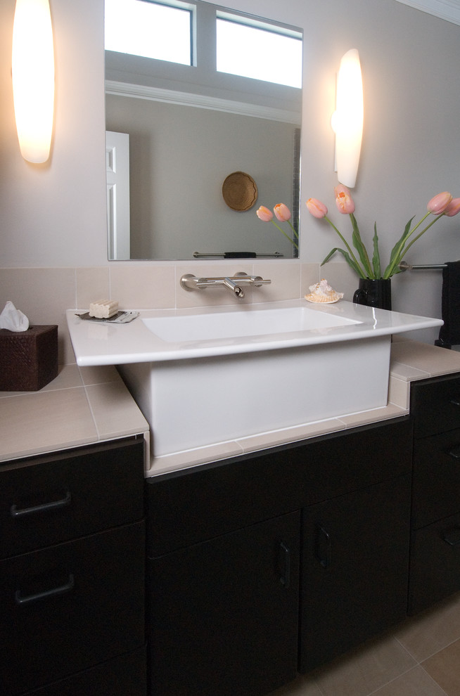 This is an example of a mid-sized asian master bathroom in San Francisco with a vessel sink, flat-panel cabinets, dark wood cabinets, tile benchtops, an open shower, a one-piece toilet, beige tile, stone tile, grey walls and limestone floors.